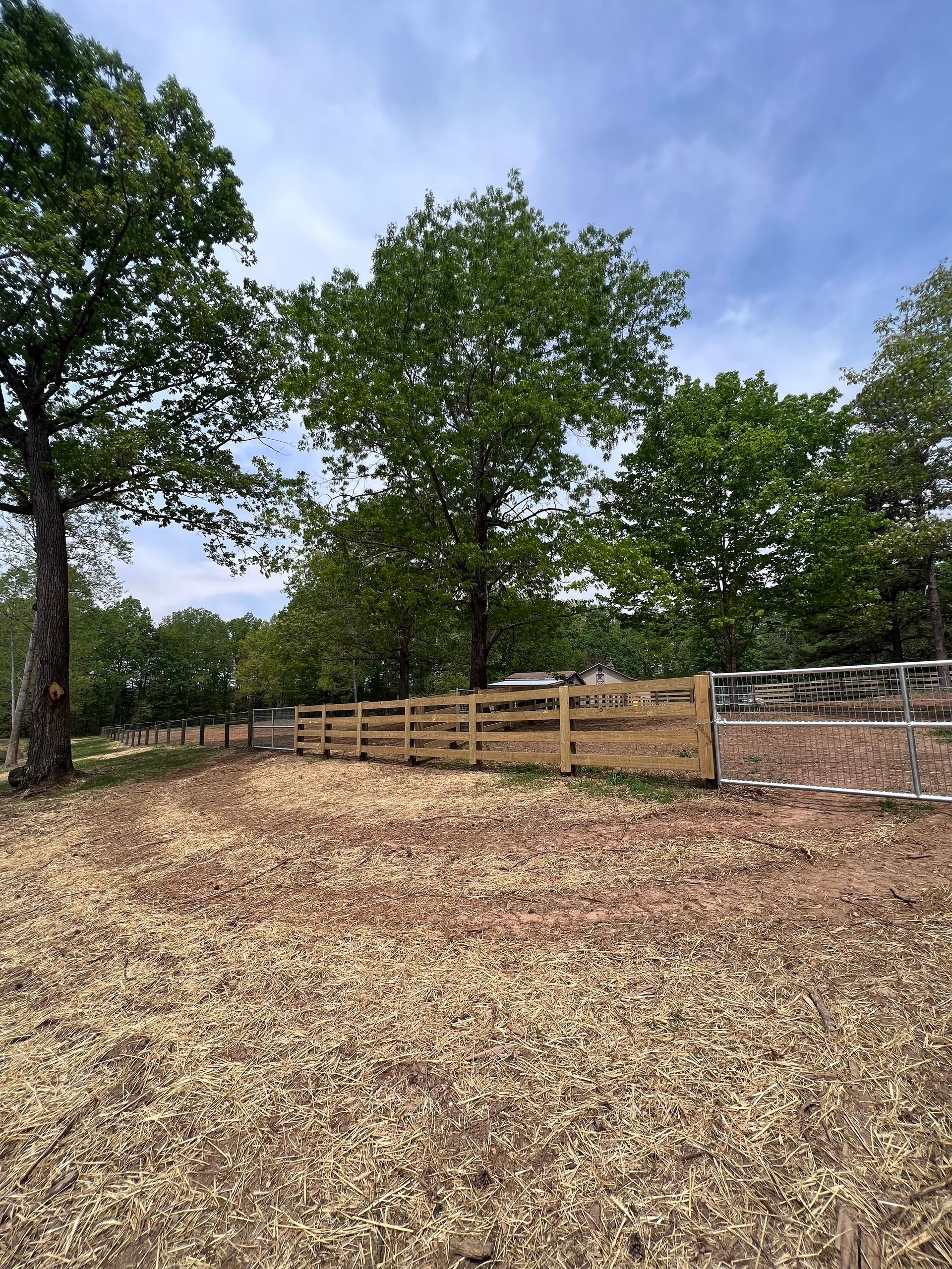 A wooden fence in a field with trees in the background