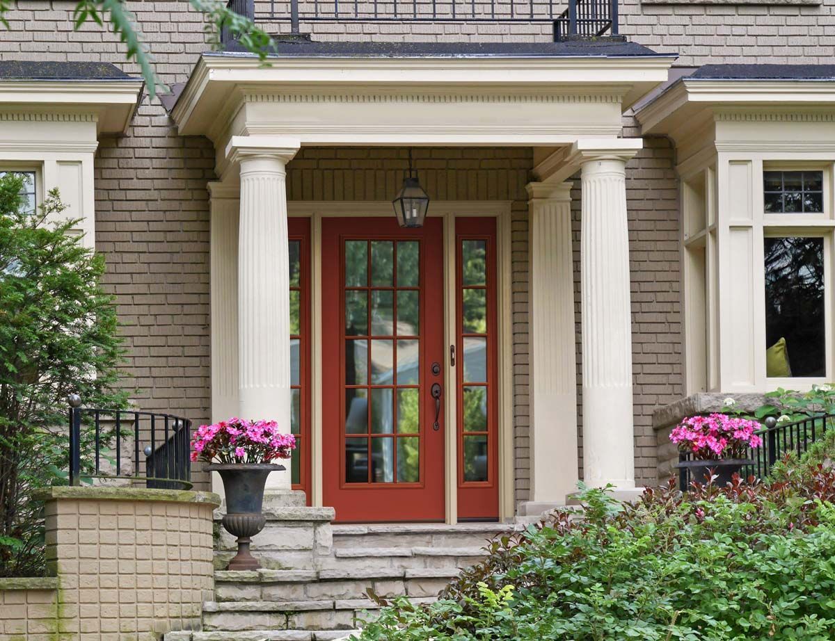 The front door of a brick house with red doors