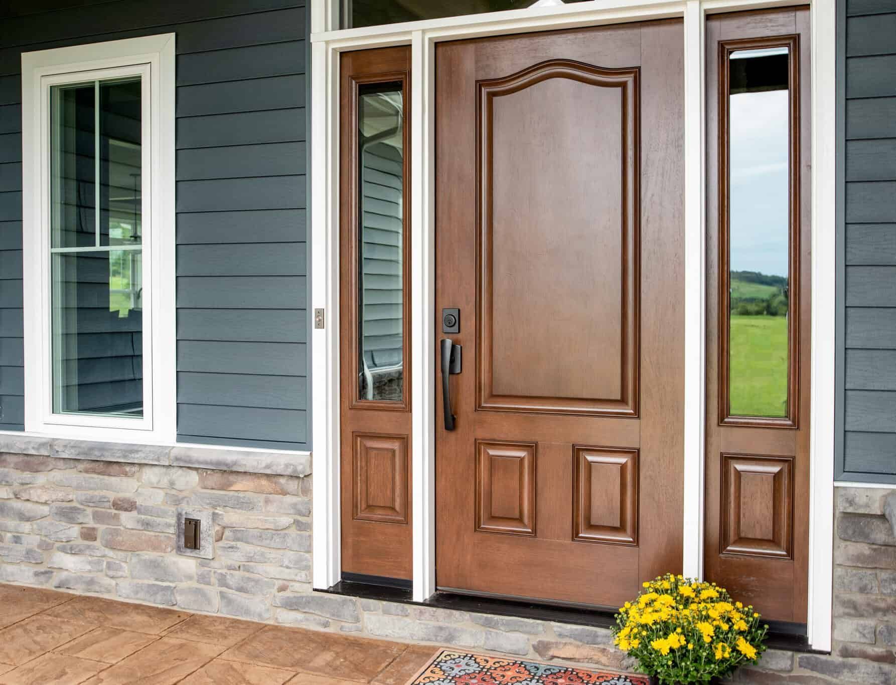 The front door of a house with a wooden door and two windows.