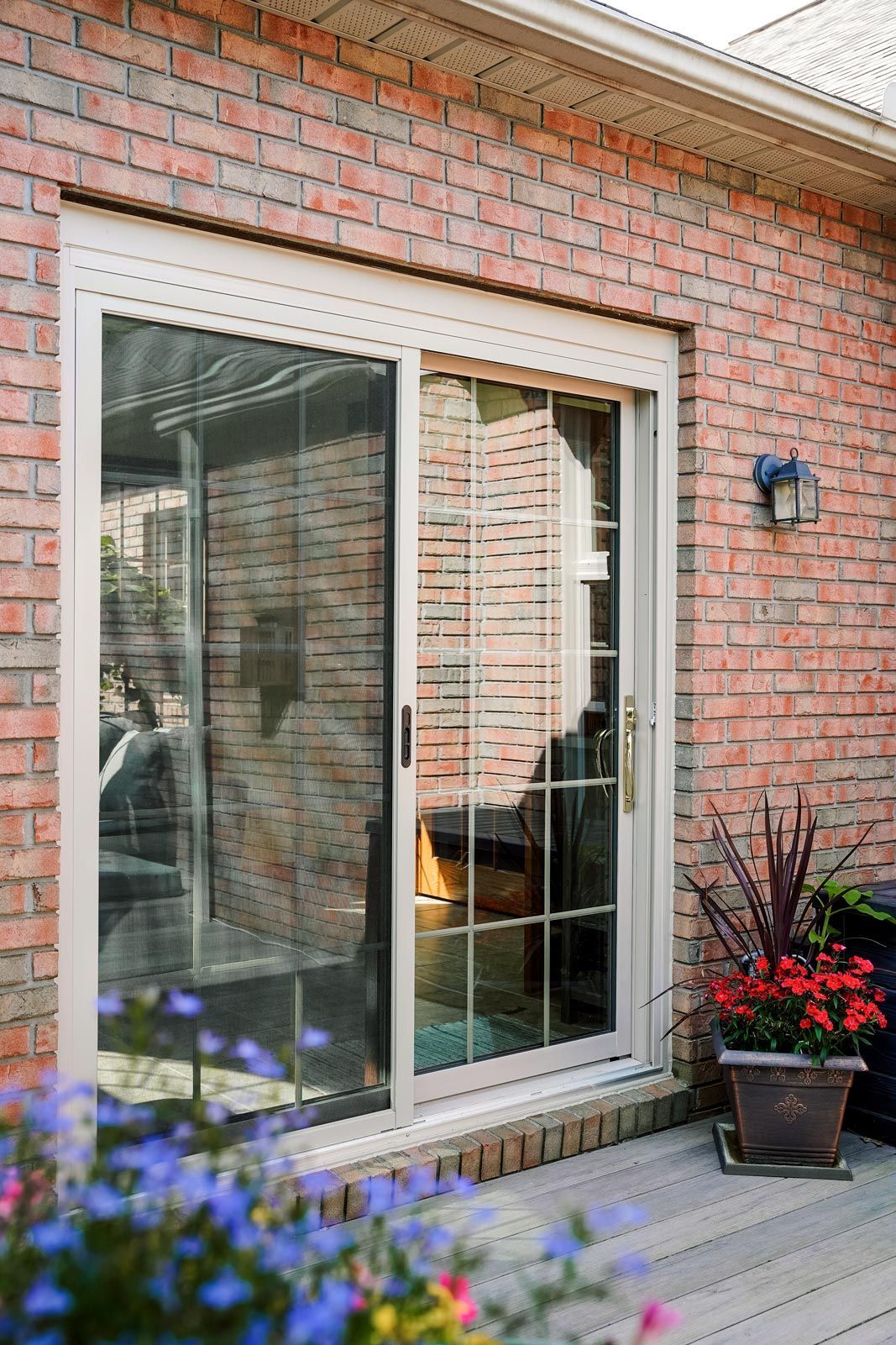 A brick house with a sliding glass door and flowers in front of it.