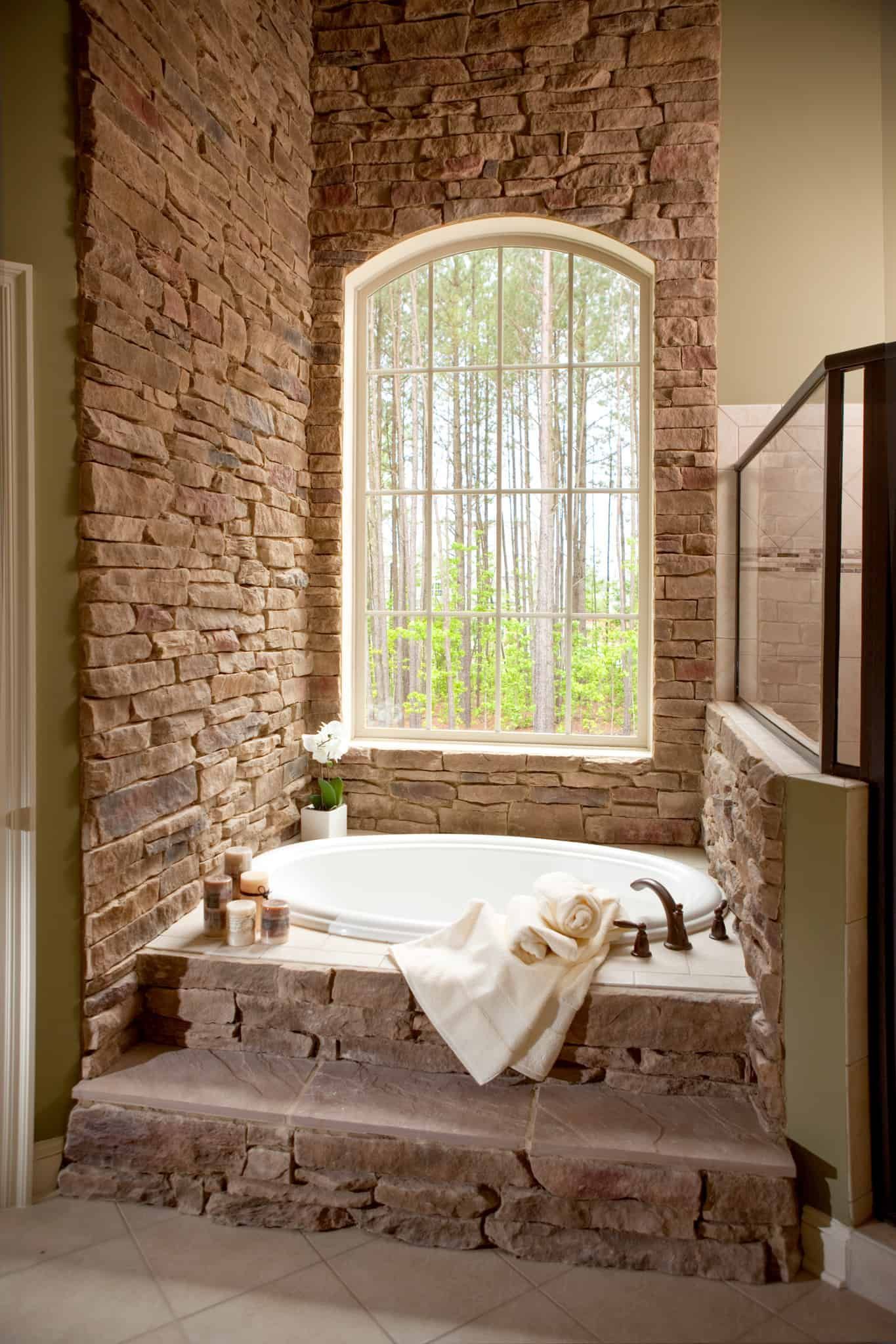 A bathroom with a jacuzzi tub and a brick wall.