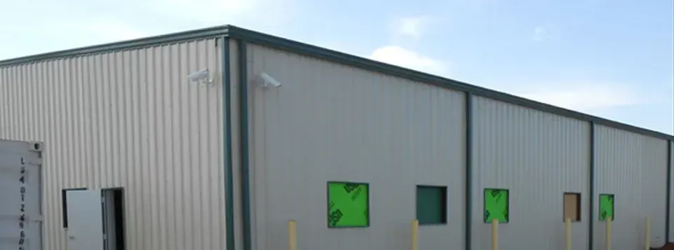 Gray industrial building with green windows on a clear day