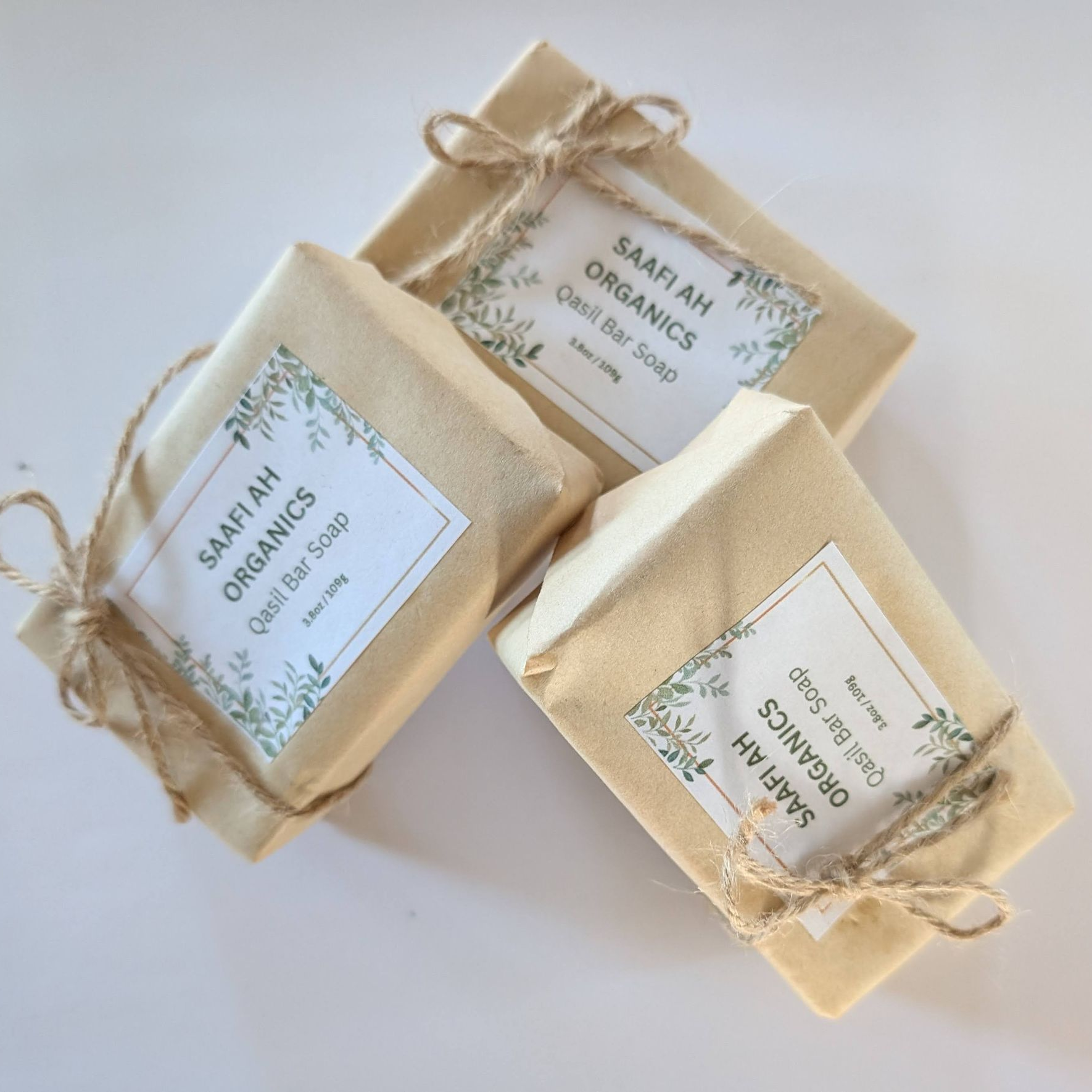 Three wrapped soap bars with labels and twine, on a white surface.