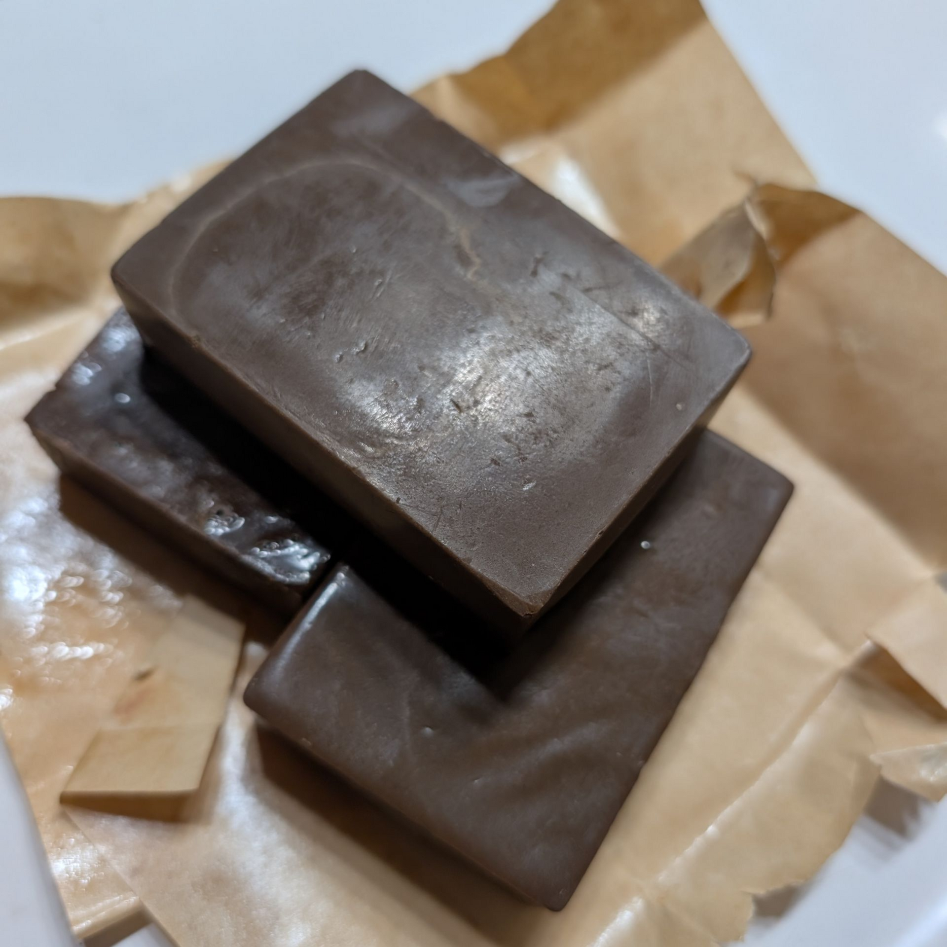 Three dark chocolate bars stacked on brown paper.
