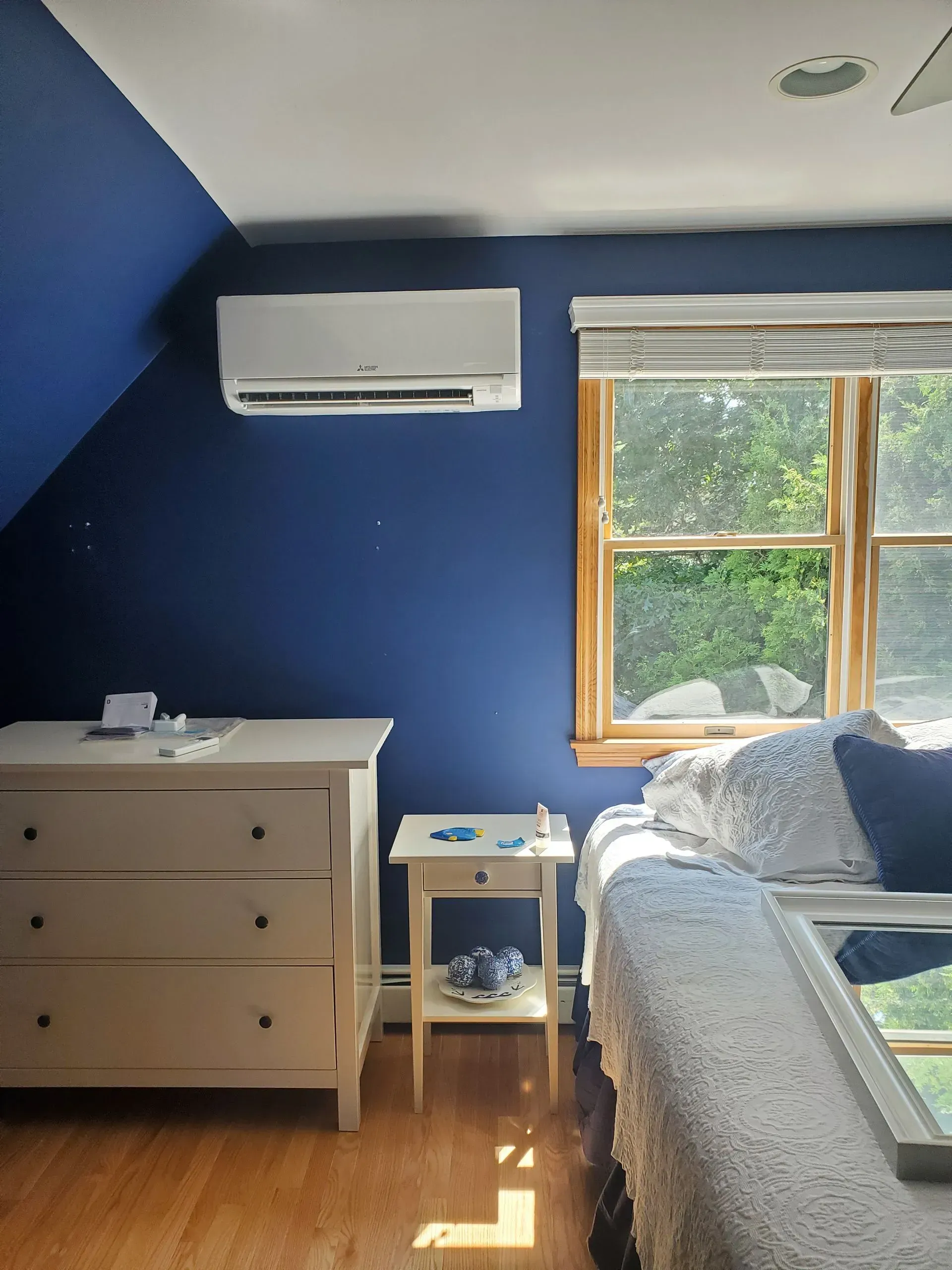 Blue bedroom with a window, white dresser, and an air conditioner.