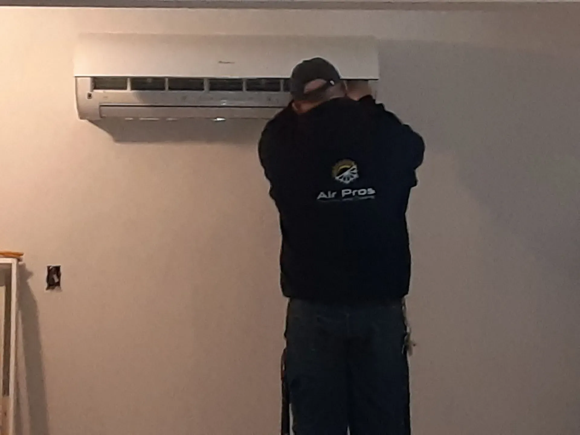 Person installing an air conditioner on a wall.