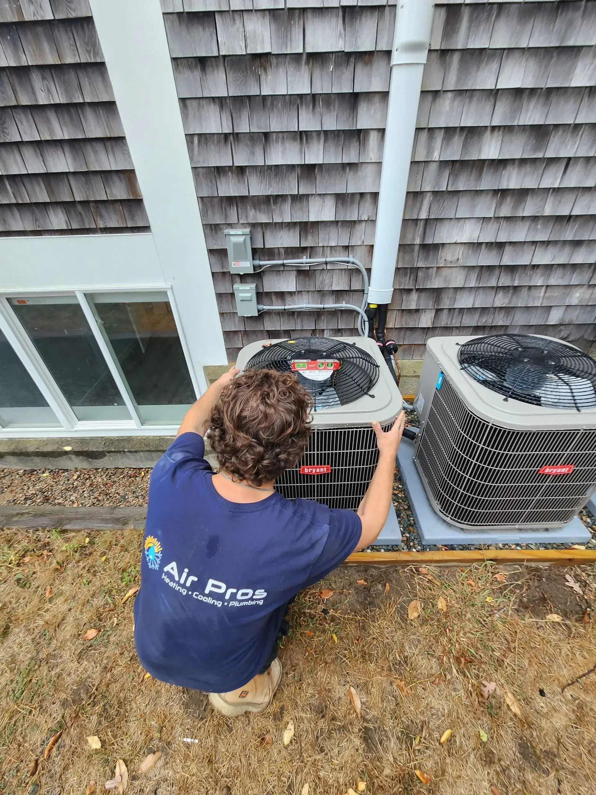 HVAC technician inspecting an air conditioning unit outside a house.