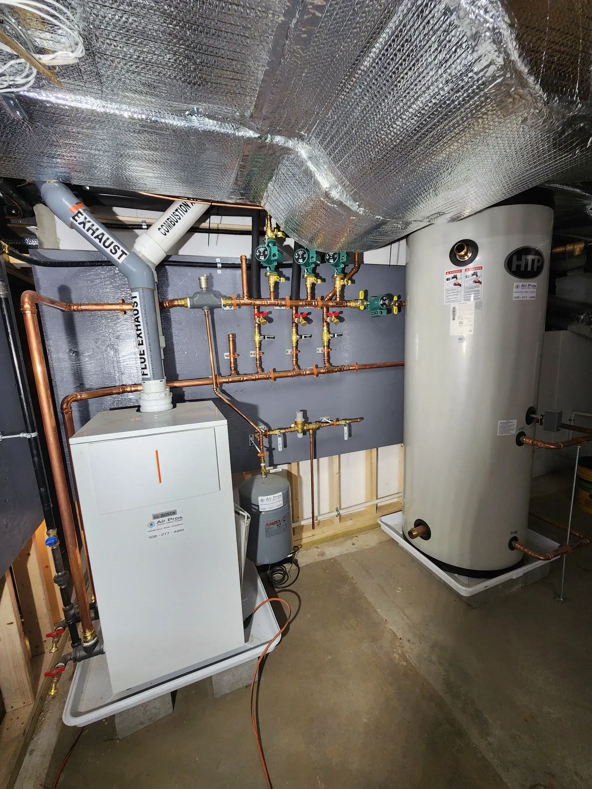 A basement with a heating system, water heater, copper pipes, and a gray water expansion tank.