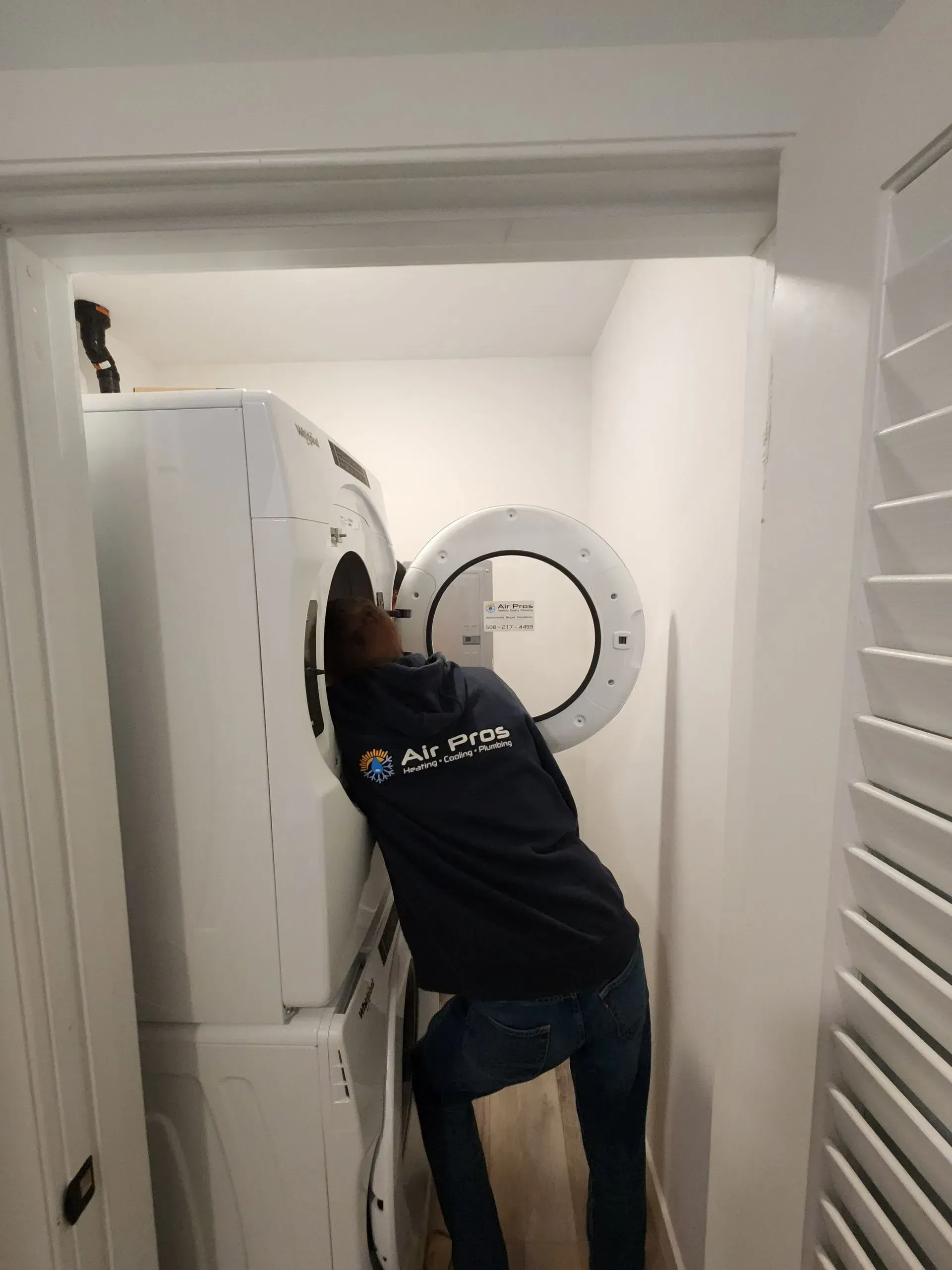 Person leaning into a washing machine inside a white closet.
