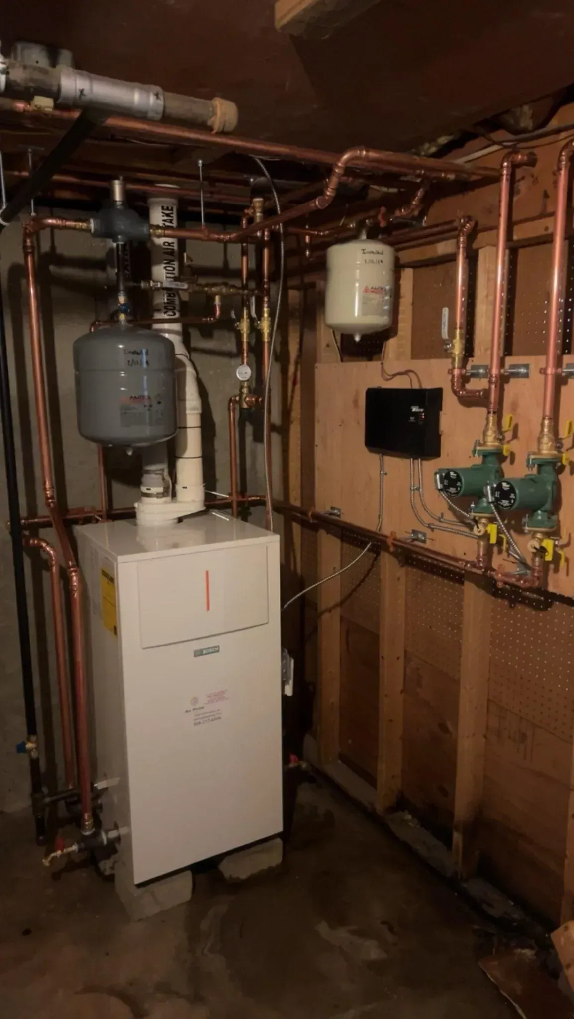 Copper pipes and furnace in a basement setting.