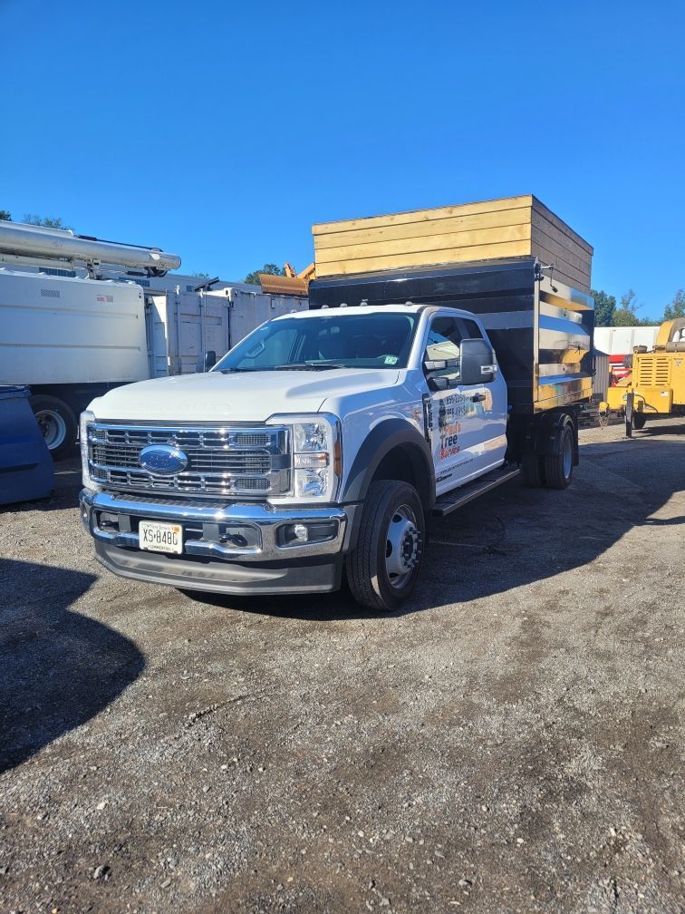 White dump truck parked on a gravel lot under a clear blue sky.