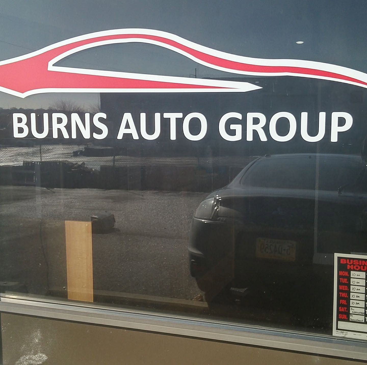 Burns Auto Group sign on dark storefront window with red car outline logo