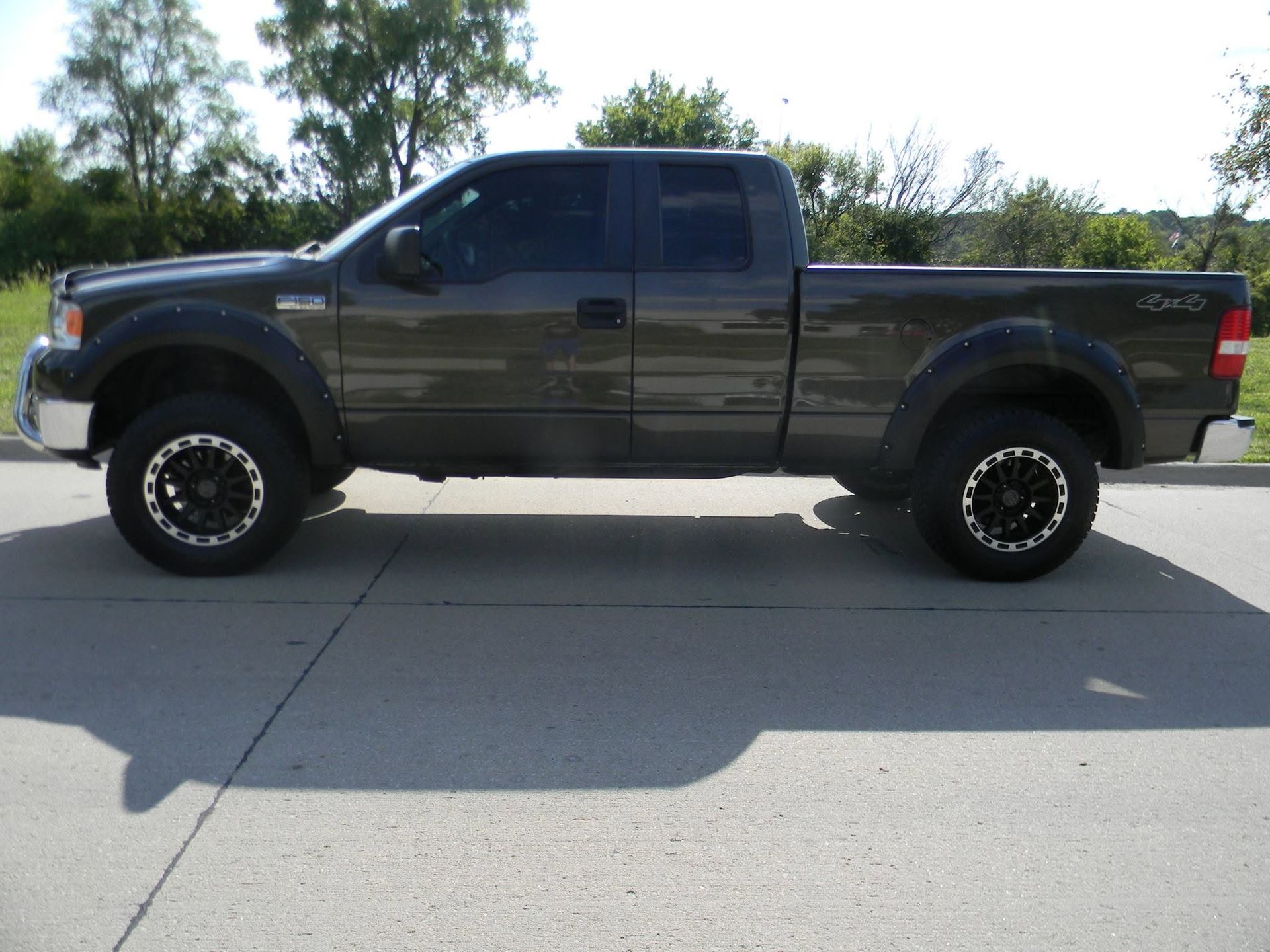 Dark gray lifted pickup truck parked on a driveway in daylight