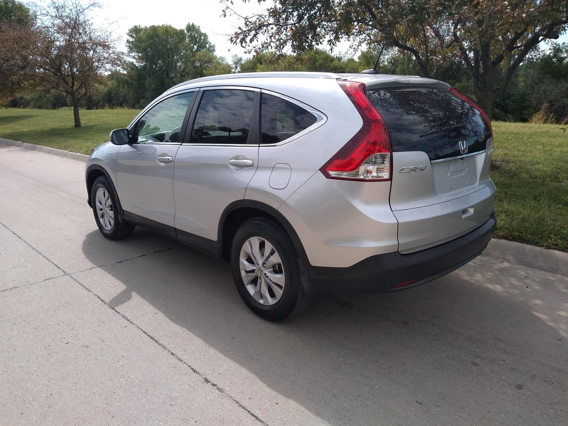 Silver SUV parked along a curb on a suburban street with trees and grass nearby