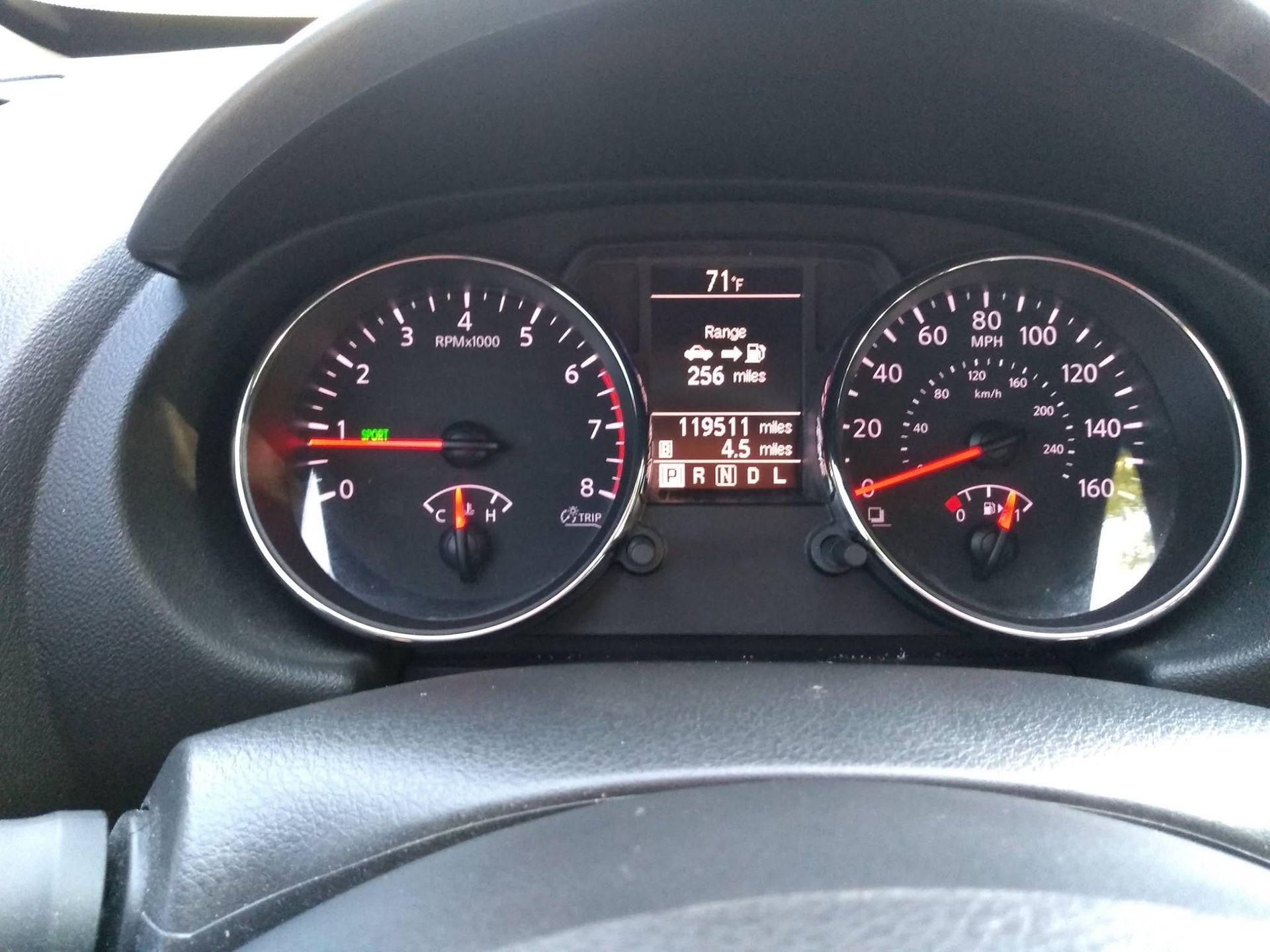 Car dashboard with illuminated gauges, showing speedometer, tachometer, and center display.