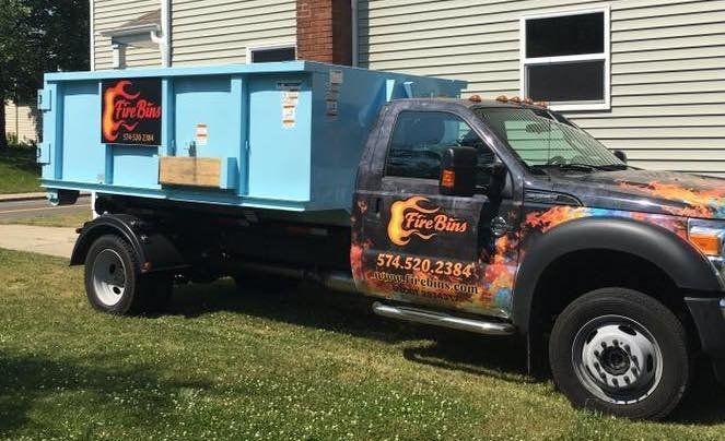 Black pickup truck towing a blue food trailer parked on grass outside a building.