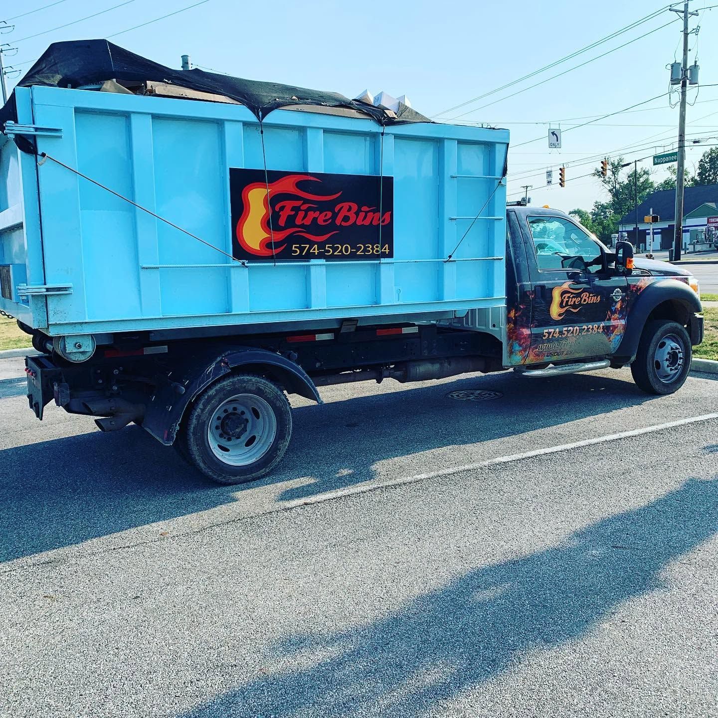 Blue dump truck with FireBird sign parked on a sunny street