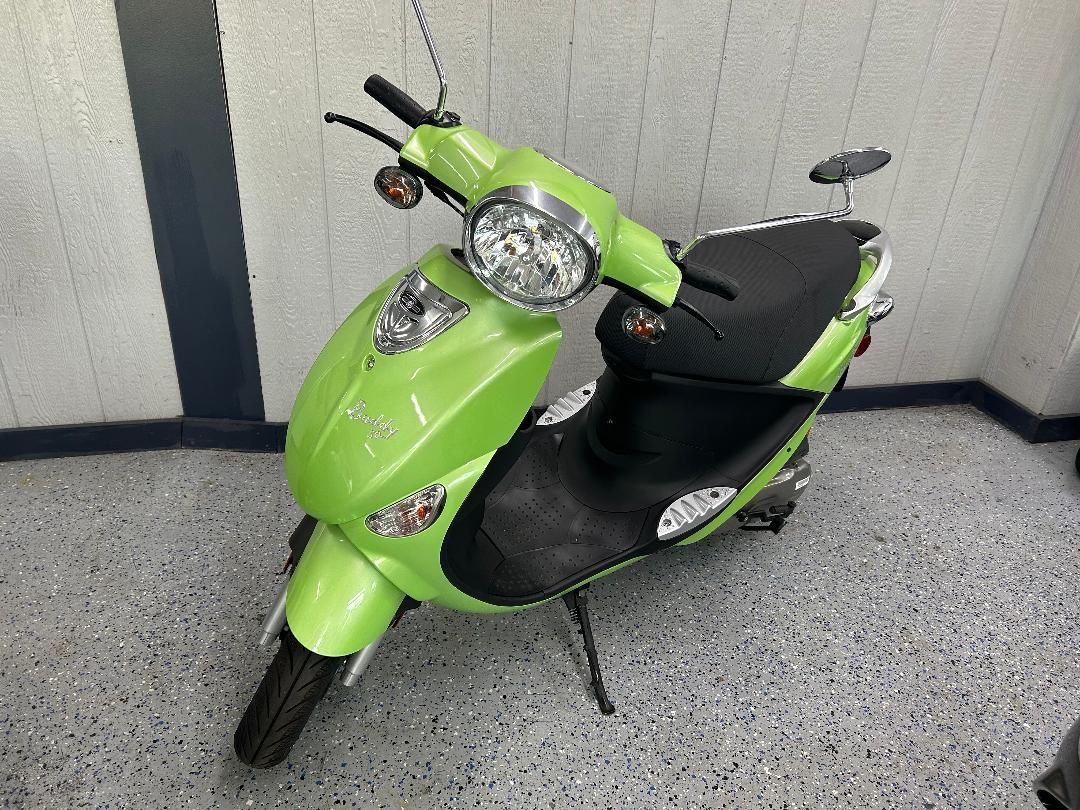 A green and black scooter is parked in a garage.