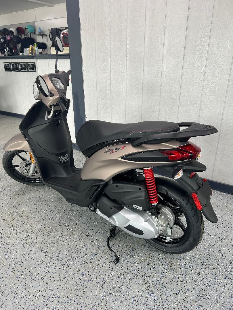 A scooter is parked in a garage next to a wall.