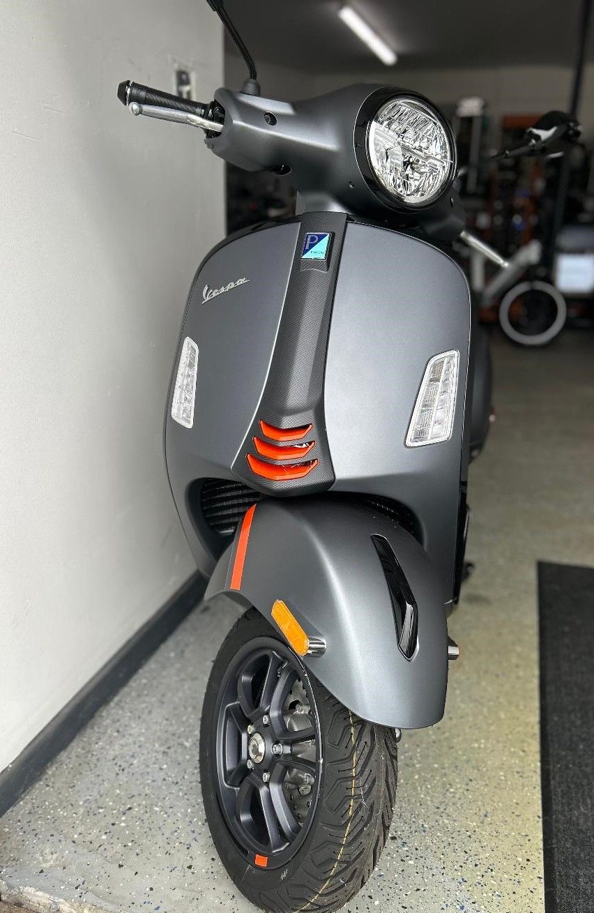 A scooter is parked in a garage next to a wall.
