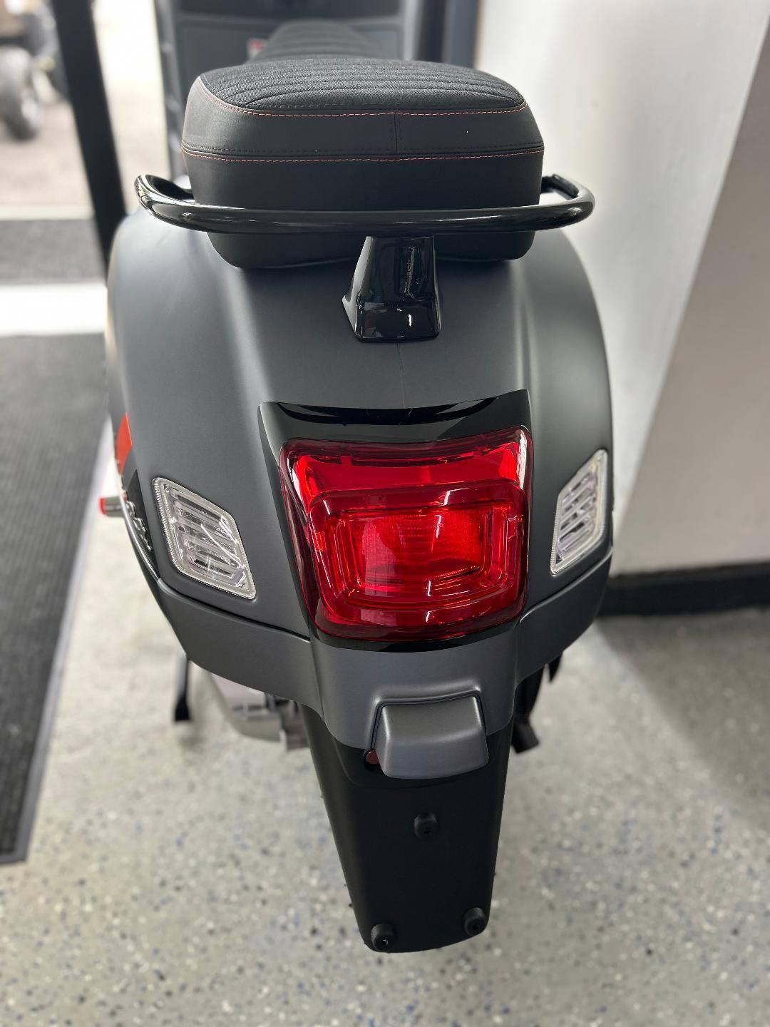 The back of a scooter is shown with a red tail light.