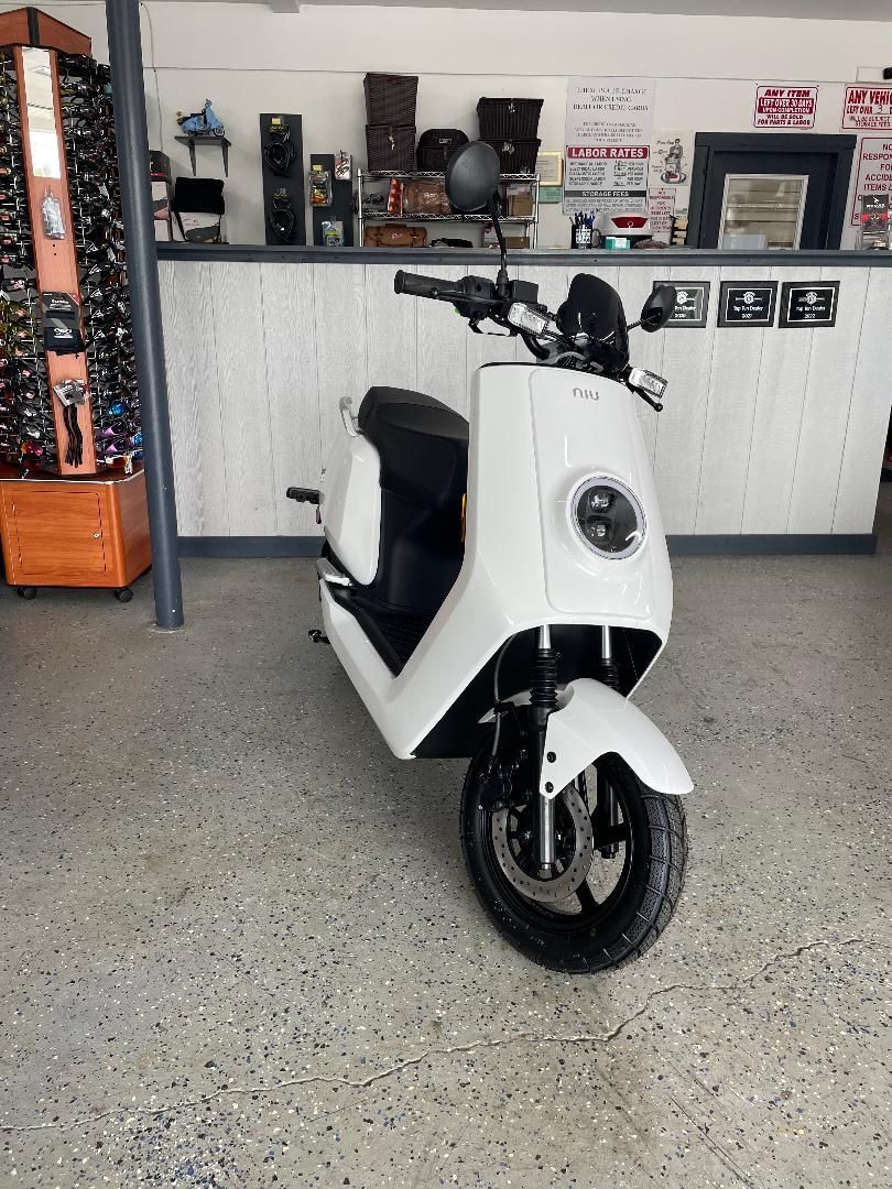A white scooter is parked in a garage next to a counter.