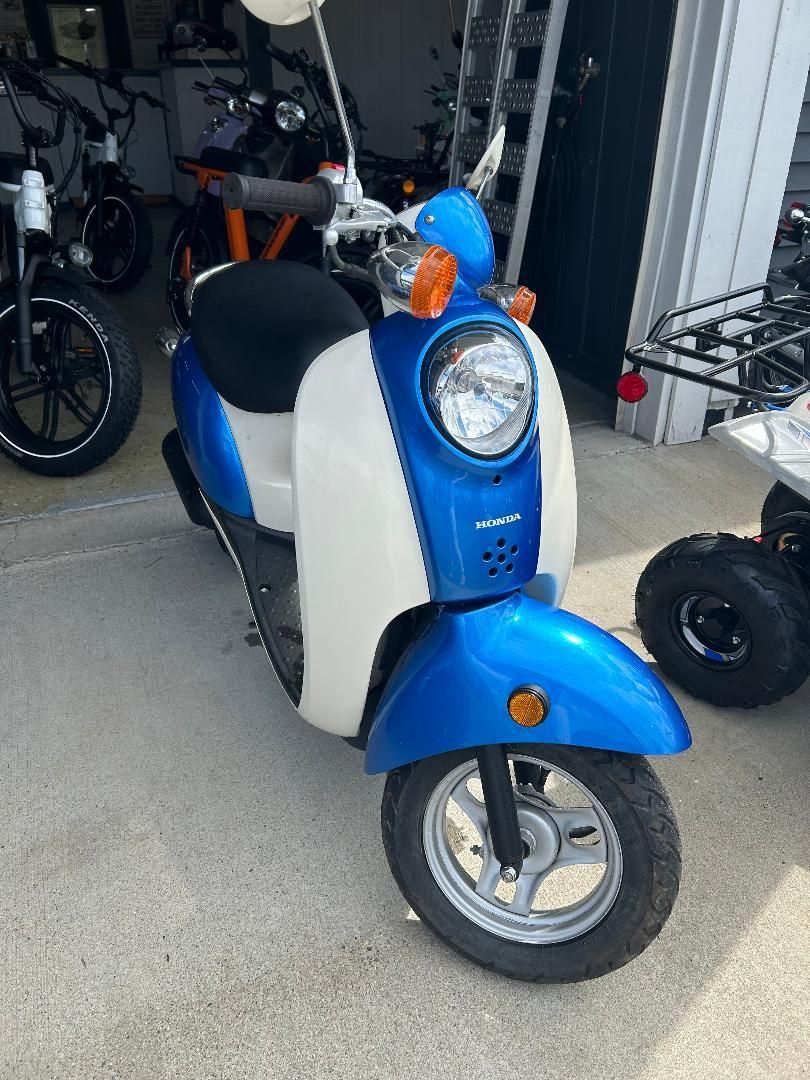A blue and white scooter is parked in a garage.