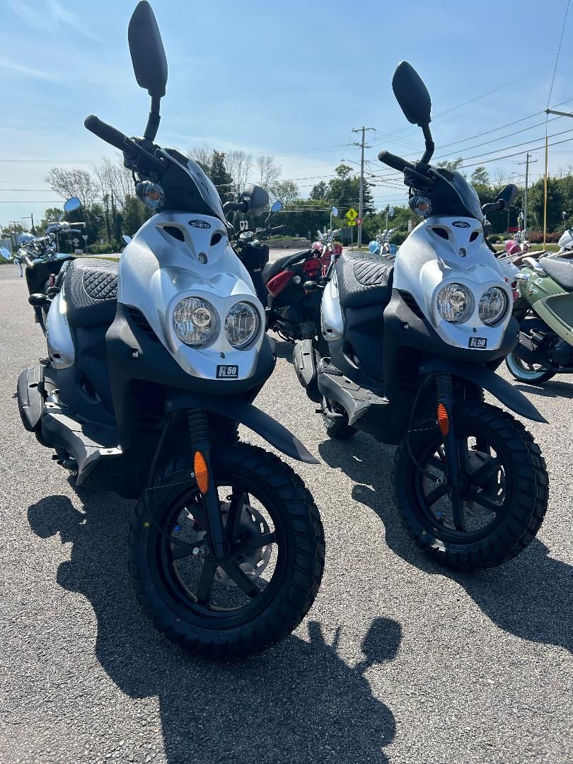 Two scooters are parked next to each other in a parking lot.