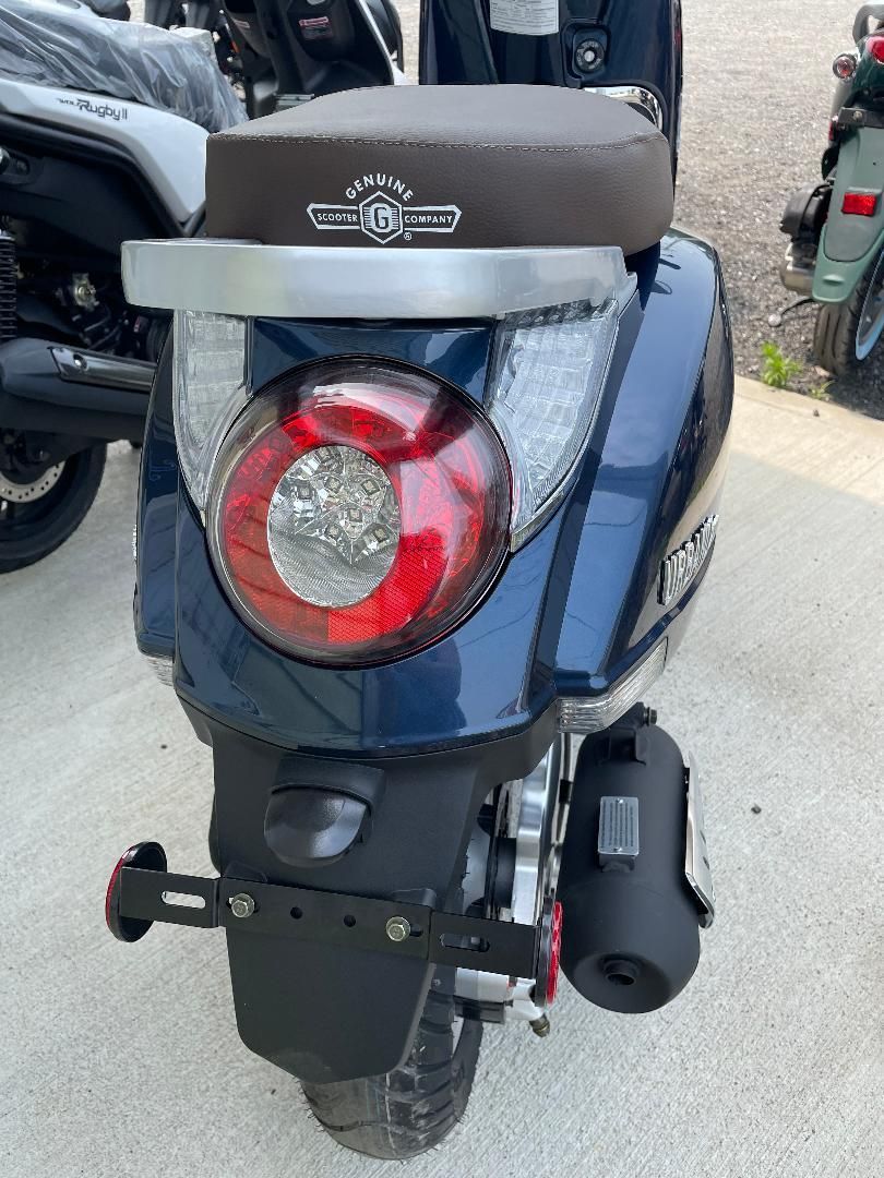 A blue scooter with a brown seat is parked on the side of the road.
