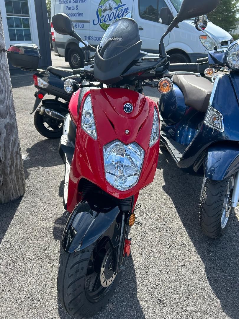 A red scooter is parked next to a blue scooter in a parking lot.
