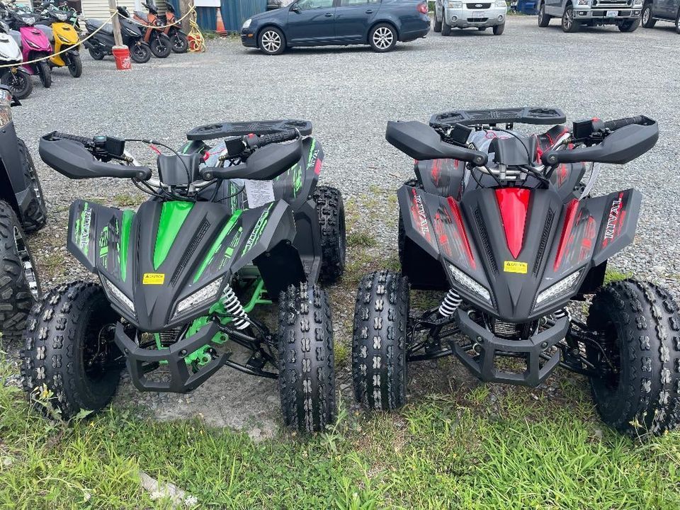 Two atvs are parked next to each other in a grassy field.