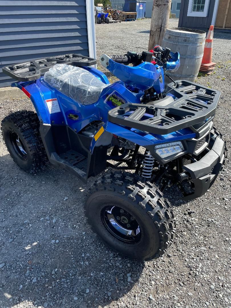 A blue atv is parked in a gravel lot.