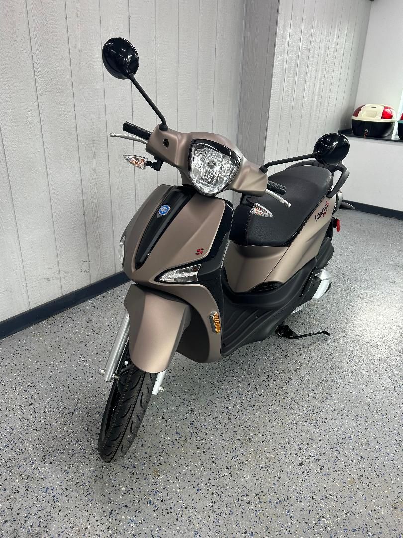 A scooter is parked in a garage next to a wall.