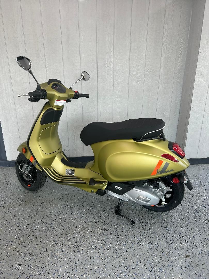 A yellow scooter is parked in a garage next to a wall.