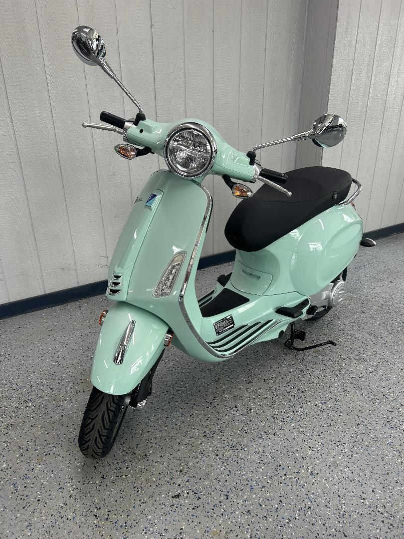 A mint green scooter is parked in a garage.