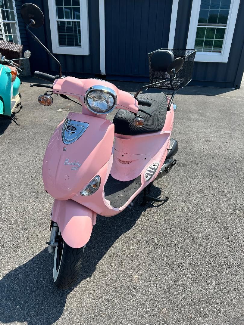 A pink scooter is parked in front of a building.