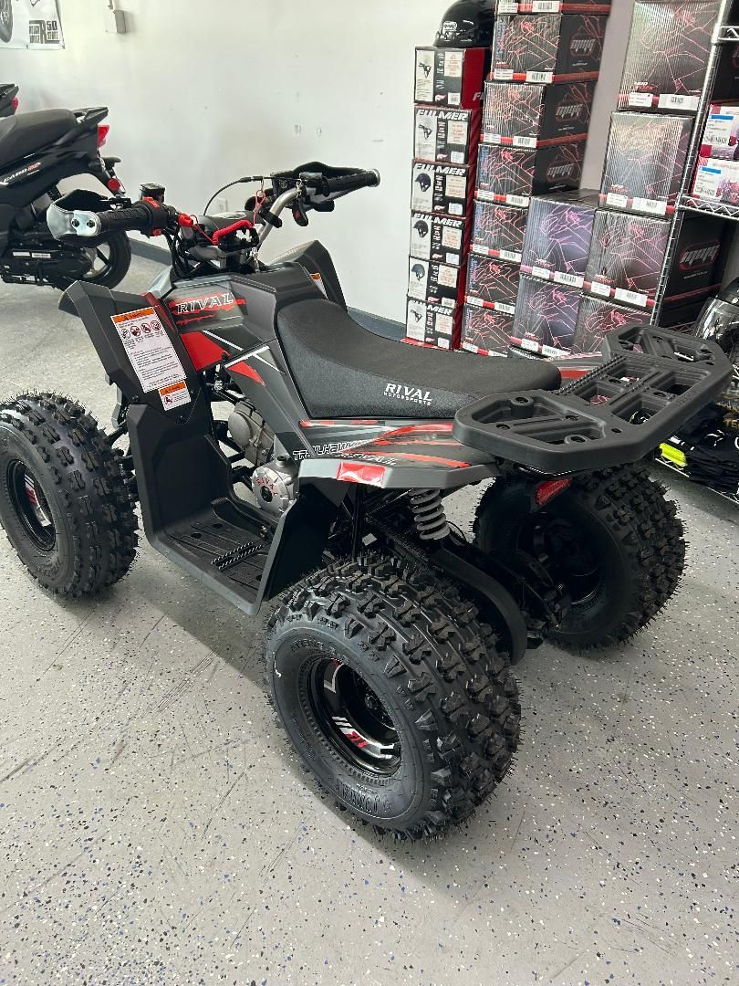 A black and red atv is parked in a garage.