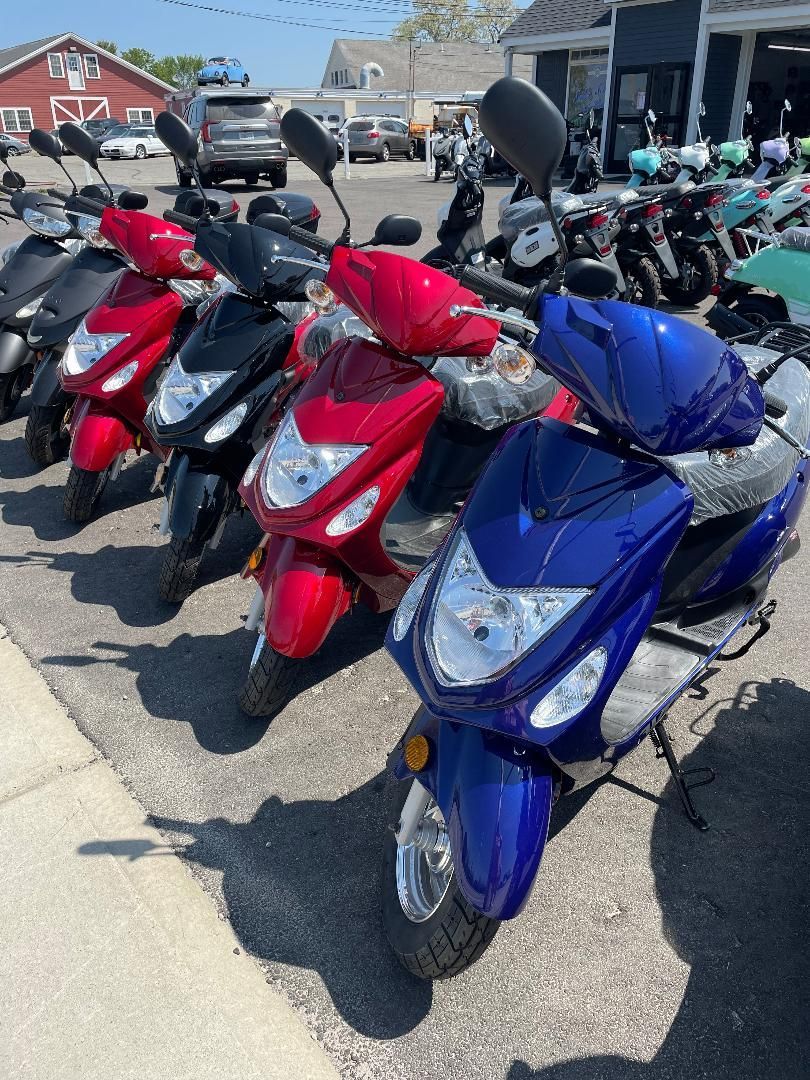 A row of scooters are parked in a parking lot