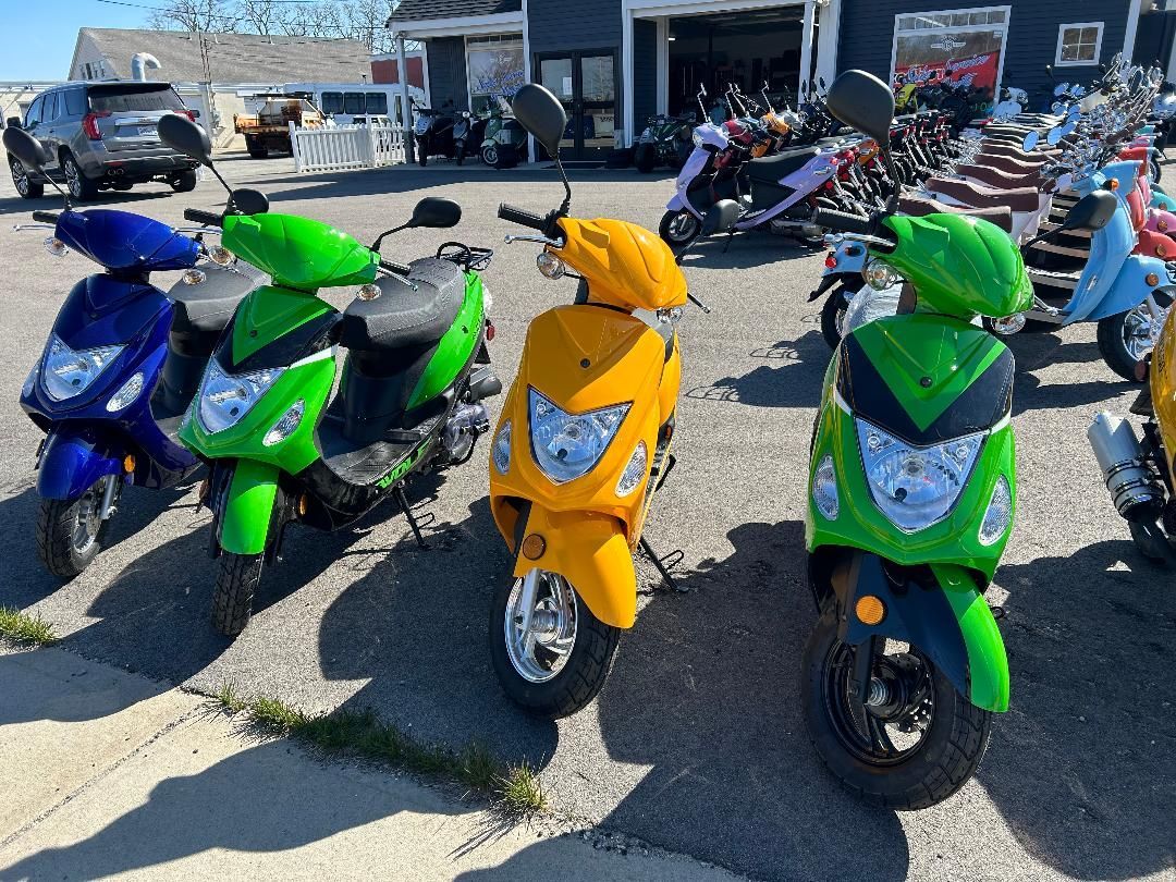 A group of scooters are parked next to each other on the side of the road.