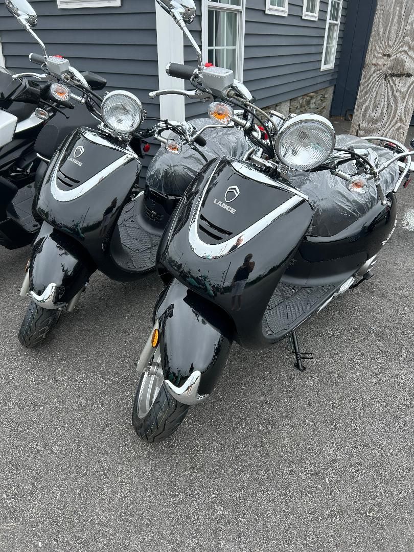 A row of black scooters are parked in front of a building.