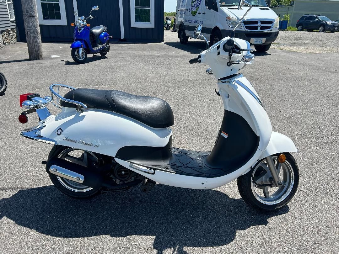 A white scooter is parked in a parking lot in front of a building.