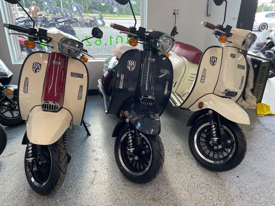 Three scooters are parked next to each other in a garage.