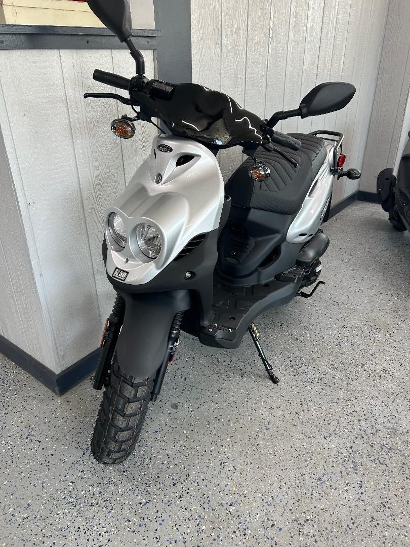 A scooter is parked in a garage next to a wall.