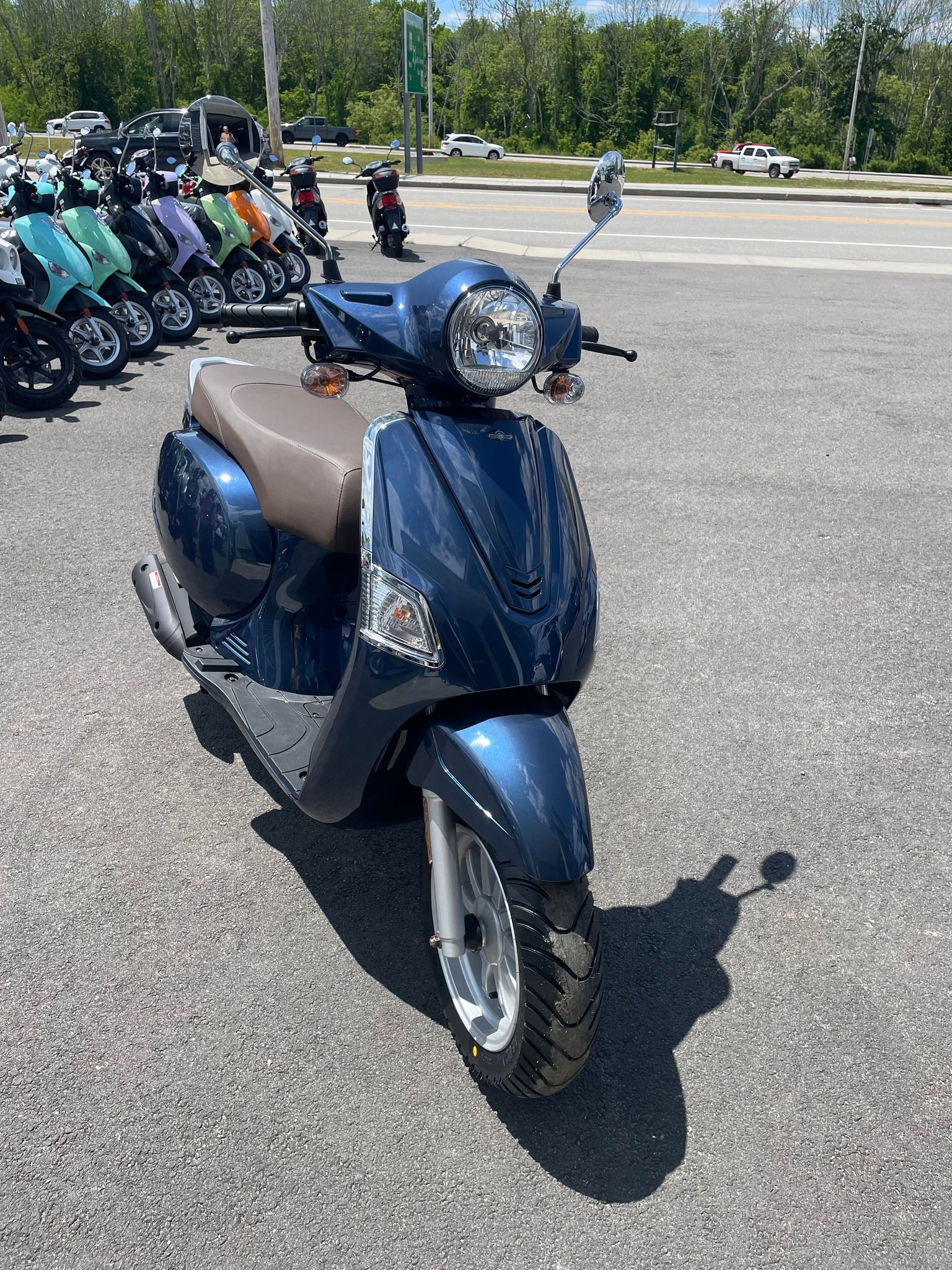 A blue scooter is parked in a parking lot next to a row of other scooters.