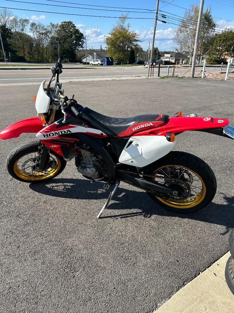 A red and white dirt bike is parked on the side of the road.