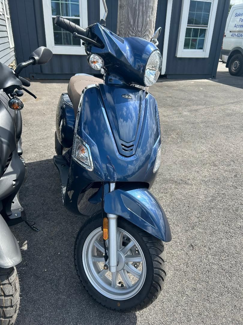 A blue scooter is parked in front of a building.