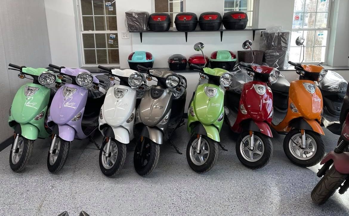 A row of scooters are parked in a garage.
