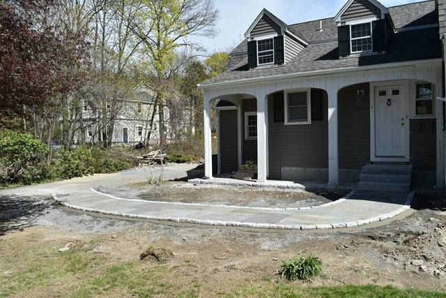 Gray house with a front porch and curved driveway, surrounded by trees and a bare yard