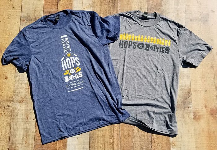 two t-shirts are sitting on top of each other on a wooden table