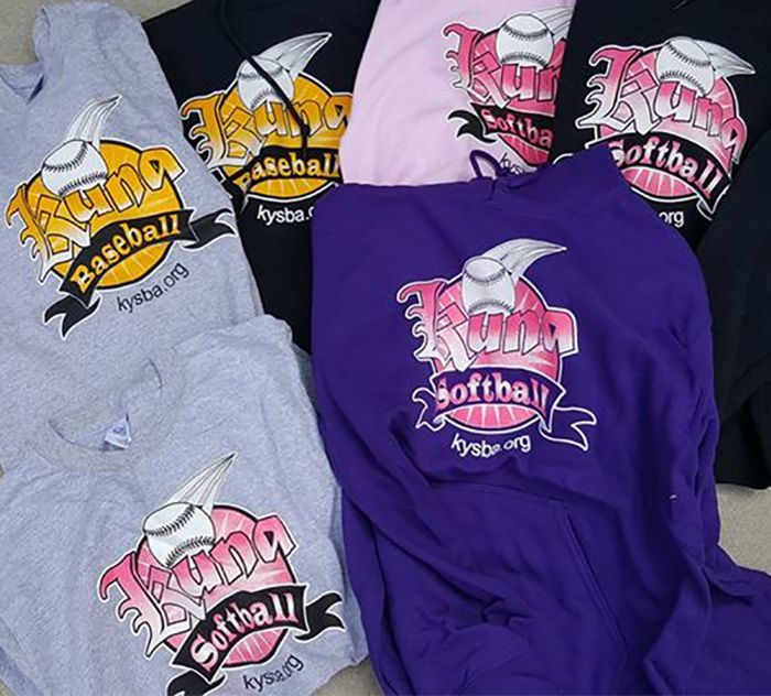 a bunch of baseball and softball shirts are stacked on top of each other